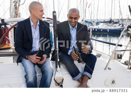Latin American and European businessmen sit and drink beer on the yacht in seaport 88917331