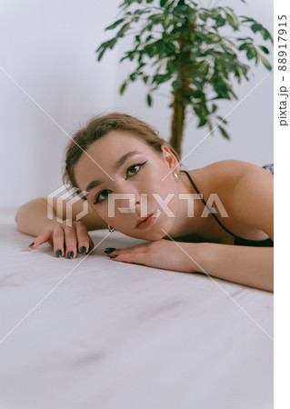Portrait of young caucasian woman in red cloth laying near flowerpot Portrait of young caucasian woman in red cloth laying near flowerpot 88917915