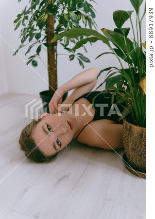 Portrait of young caucasian woman in red cloth laying near flowerpot Portrait of young caucasian woman in red cloth laying near flowerpot 88917939