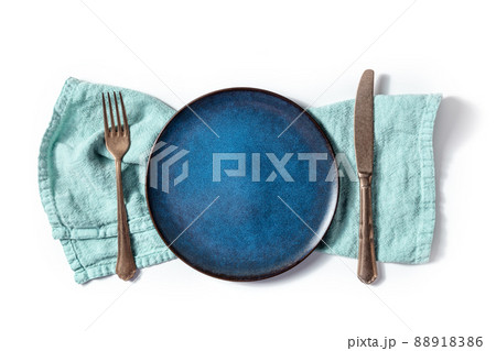 Cutlery with a blue plate. A fork, a knife, and a dish on a teal napkin 88918386