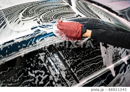 Professional car wash. Detailing worker washes the vehicle body with foam and rag 88921345