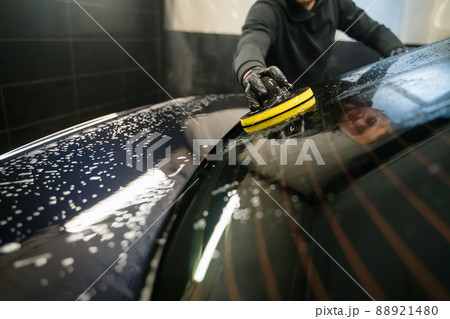 Man cleans rear window of car with  circle sponge. Professional car wash process 88921480