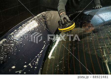 Man cleans rear window of car with  circle sponge. Professional car wash process 88921481