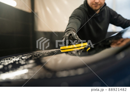 Man cleans rear window of car with  circle sponge. Professional car wash process 88921482