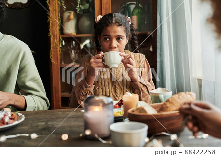 African girl sitting at table with cake and drinking tea together with her family 88922258