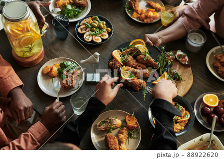 High angle view of family sitting at dining table and eating chicken together during holiday event High angle view of family sitting at dining table and eating chicken together during holiday event 88922620