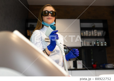 Female cosmetologist with a laser for hair removal 88922752