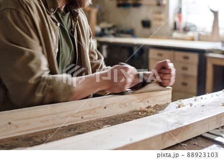 Professional male carpenter working in workshop using hand plane to smooth wooden plank surface Professional male carpenter working in workshop using hand plane to smooth wooden plank surface 88923103