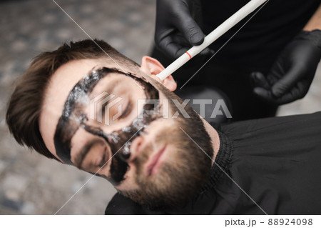 Man in a beauty salon is removing earwax using candles Man in a beauty salon is removing earwax using candles 88924098