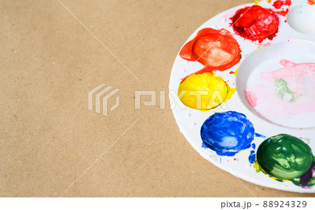 Top view of plastic palette with colorful watercolour on brown paper. Copy space 88924329