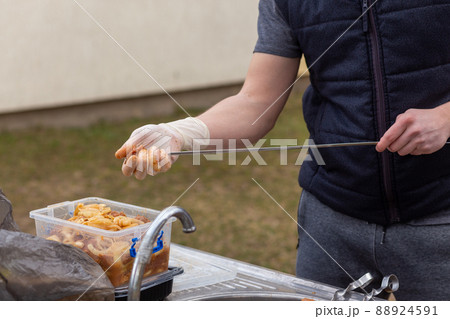 Male hands in white gloves stringing raw meat in marinade on skewers 88924591