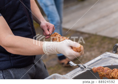 Male hands in white gloves stringing raw meat in marinade on skewers 88924592