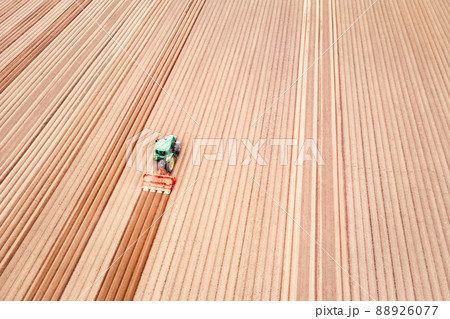 Lonely tractor on agricultural field with rows of plowed soil 88926077