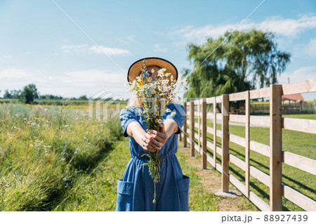 Agritourism and Farm Tours, Farm Cottagecore Weekend Trip. Farm Trips For Peaceful Weekend. A woman in rustic dress and with wildflowers in front of straw bales 88927439