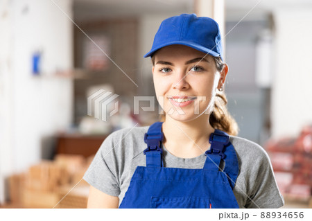 Smiling young female builder in blue uniform at construction site 88934656