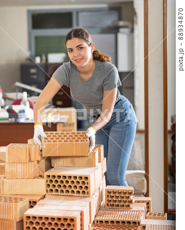 Girl stacking red bricks in her apartment during renovations 88934870