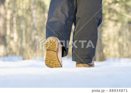 Woman walking on snow in winter forest. Focus on sole of show with snow. Woman walking on snow in winter forest. Focus on sole of show with snow. 88934871