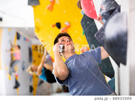 Young man having telephone conversation while climbing in bouldering centre 88935009