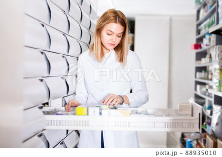 Female pharmacist offers medicine in a modern pharmacy Female pharmacist offers medicine in a modern pharmacy 88935010