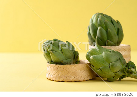 Green artichoke in bamboo basket on yellow background, Edible flower bud Green artichoke in bamboo basket on yellow background, Edible flower bud 88935626