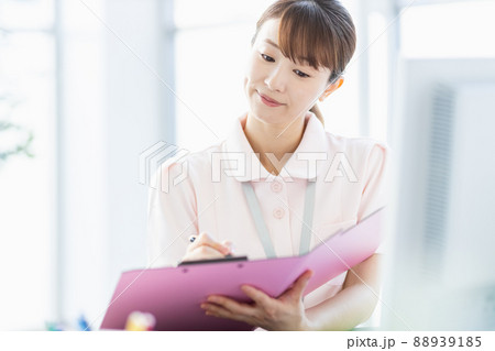 施設内でファイルに記入している医療従事者の女性 88939185