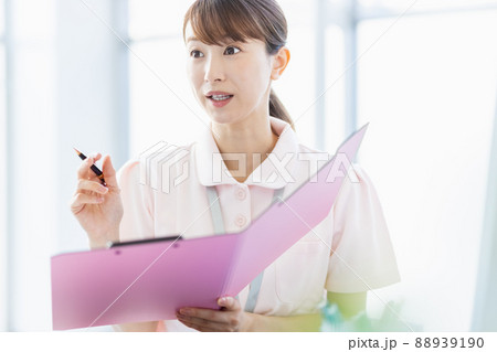施設内でファイルに記入している医療従事者の女性 施設内でファイルに記入している医療従事者の女性 88939190