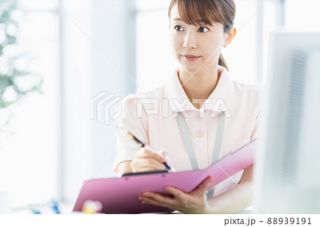 施設内でファイルに記入している医療従事者の女性 施設内でファイルに記入している医療従事者の女性 88939191