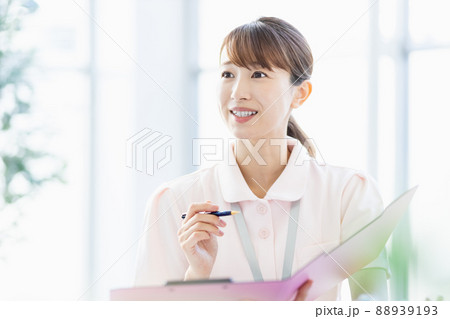 施設内でファイルに記入している医療従事者の女性 施設内でファイルに記入している医療従事者の女性 88939193