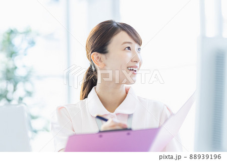 施設内でファイルに記入している医療従事者の女性 施設内でファイルに記入している医療従事者の女性 88939196