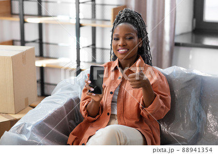 woman with phone moving home and showing thumbs up 88941354