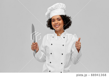 female chef in toque with knife showing thumbs up female chef in toque with knife showing thumbs up 88941368
