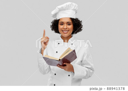 happy female chef in white toque reading cook book happy female chef in white toque reading cook book 88941378