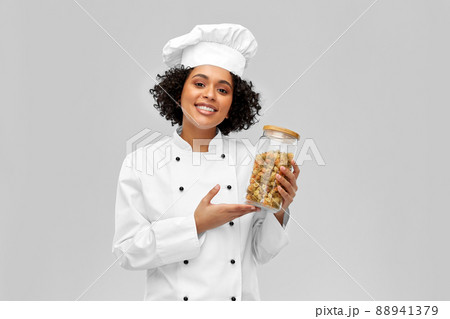smiling female chef holding jar with pasta smiling female chef holding jar with pasta 88941379