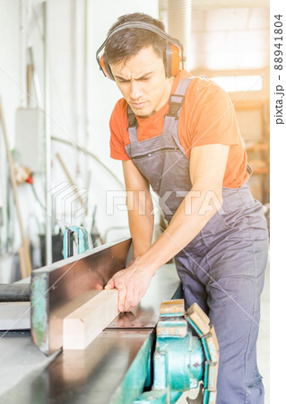 Concentrated woodworker trimming wooden plank in workshop Concentrated woodworker trimming wooden plank in workshop 88941804