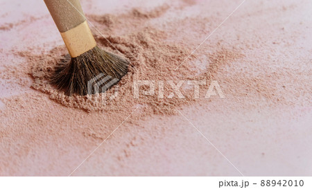 Closeup of a make-up brush, with the tip dipped into a pile of brown cosmetic foundation powder. 88942010
