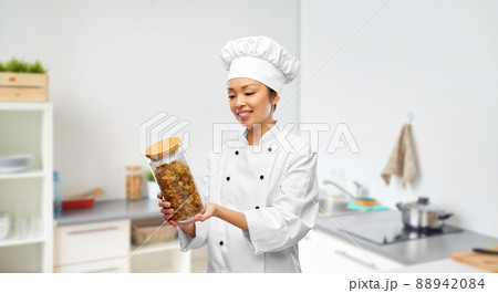 smiling female chef holding jar with pasta 88942084