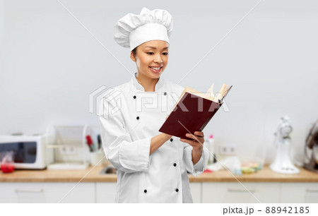 smiling female chef reading cook book smiling female chef reading cook book 88942185