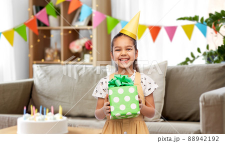 happy girl in party hat with birthday gift at home 88942192