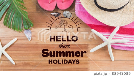 Hello there summer holidays text with starfish hat, towel and palm leaf at table with copy space 88945089