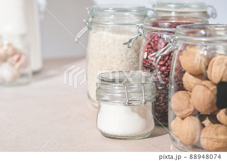 glass jars with grains, nuts and sugar on a kitchen table. sustainable home grocery storage and zero plastic house. eco friendly kitchen. glass jars with grains, nuts and sugar on a kitchen table. sustainable home grocery storage and zero plastic house. eco friendly kitchen. 88948074