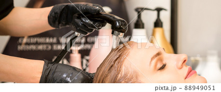 Young caucasian woman with closed eyes getting washing hair by a professional hairdresser in a beauty hair salon 88949051