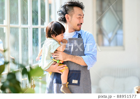 1歳10ヶ月の男の子を抱っこする髭のエプロン主夫の写真素材