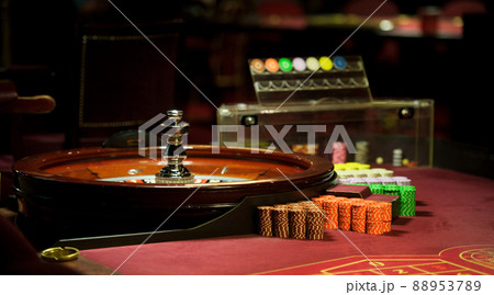 There is a red table with roulette chips in the casino 88953789