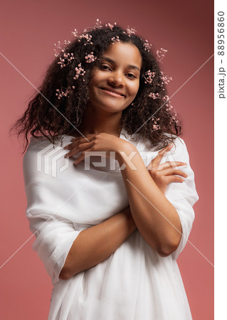 Portrait of young tender woman in white bathrobe posing, smiling at camera isolated over pink studio background 88956860