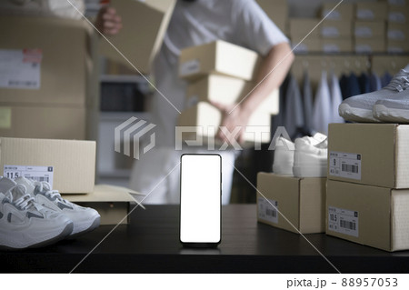 Smartphone with blank white screen standing on the desktop . Asian man online seller checking stock Smartphone with blank white screen standing on the desktop . Asian man online seller checking stock 88957053