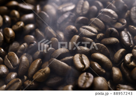 Freshly roasted pile of coffee beans with smoke on foreground. Aromatic fresh deep brown  88957243