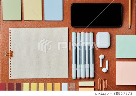 Office knolling composition of drawing markers, wireless earphones, sticky notes, gadget on leather surface in autumn colors Office knolling composition of drawing markers, wireless earphones, sticky notes, gadget on leather surface in autumn colors 88957272