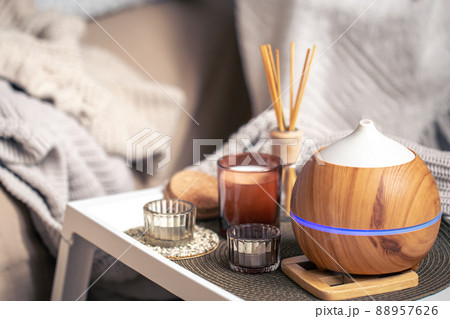 A cozy composition with an aroma diffuser and candles in a home interior. A cozy composition with an aroma diffuser and candles in a home interior. 88957626