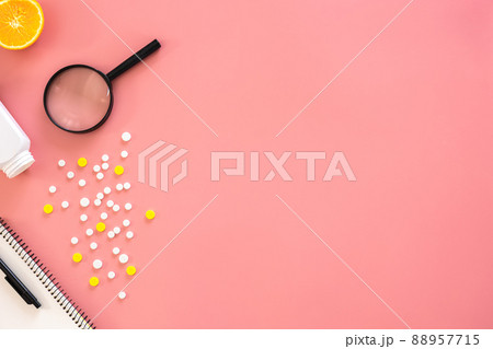 Flat lay, pills and magnifier on pink background, copy space. 88957715