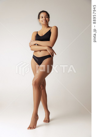 Full-length portrait of young slim woman posing in black underwear isolated over grey background Full-length portrait of young slim woman posing in black underwear isolated over grey background 88957945